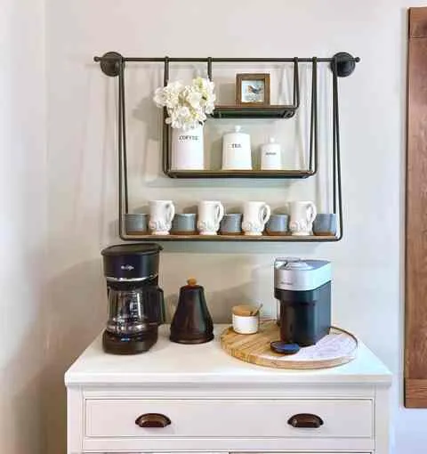 A coffee station with mugs on an open shelf, a filter machine and a pod machine below