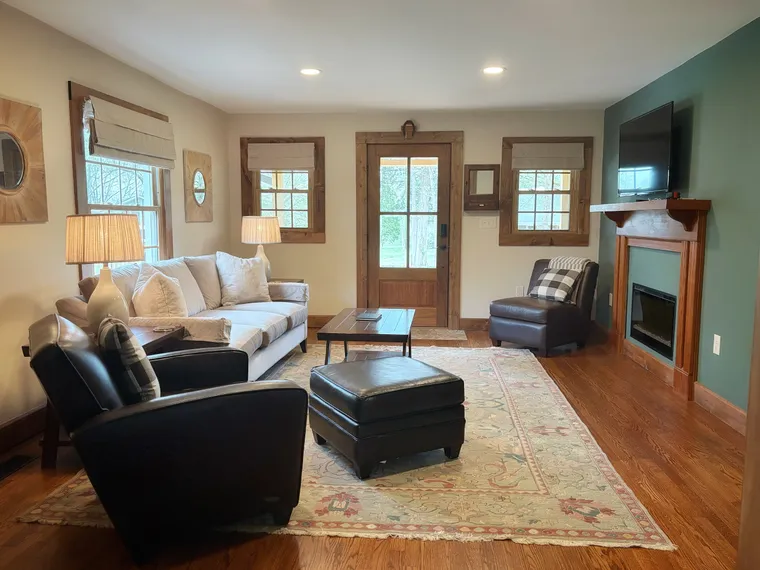 The living room with sofas drawn around a fireplace and a deep green accent wall