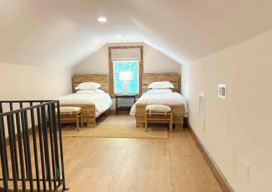 Two twin beds side by side in the loft, under the slope of the roof
